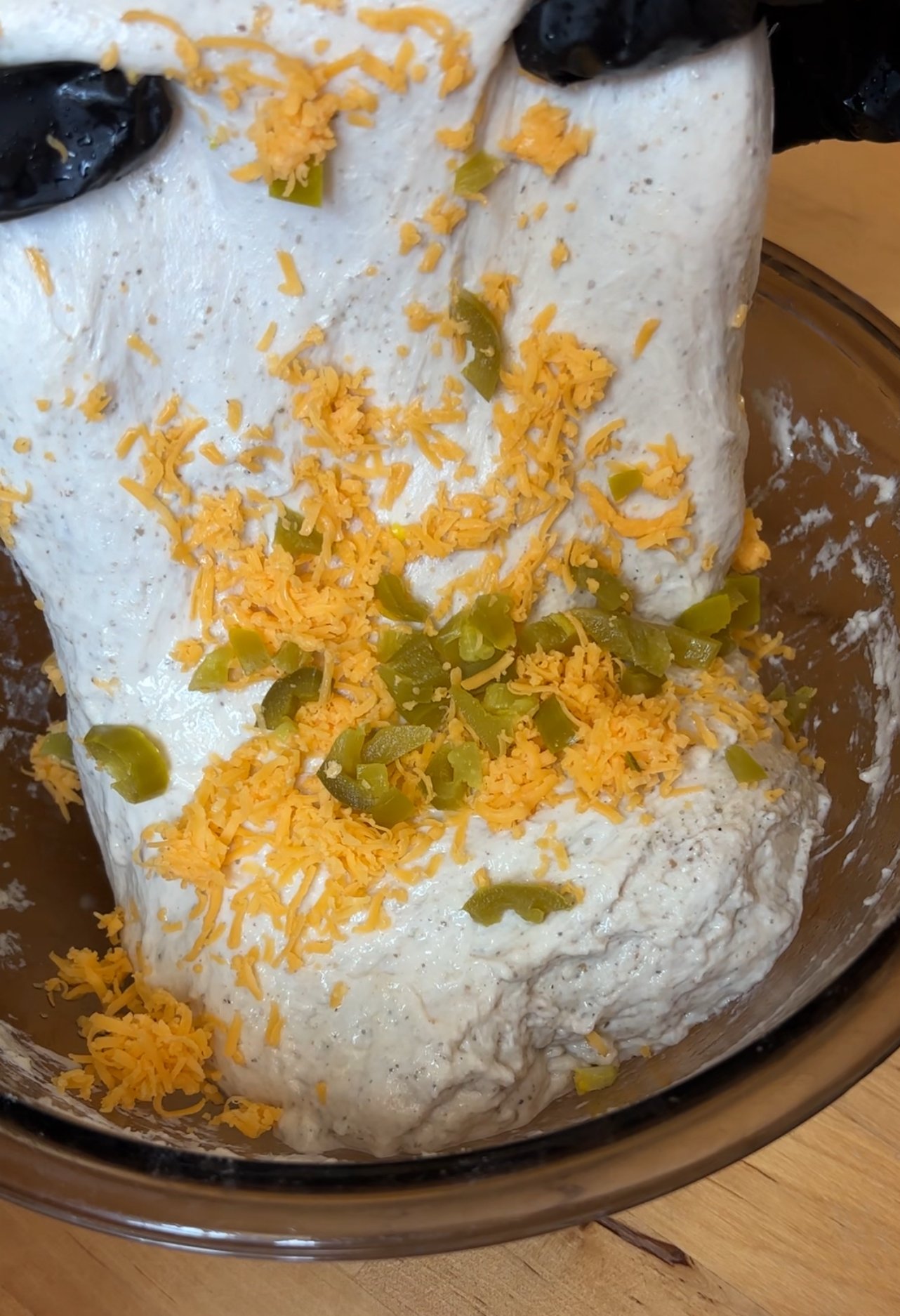 stretch and folding jalapeno and cheddar cheese in sourdough dough