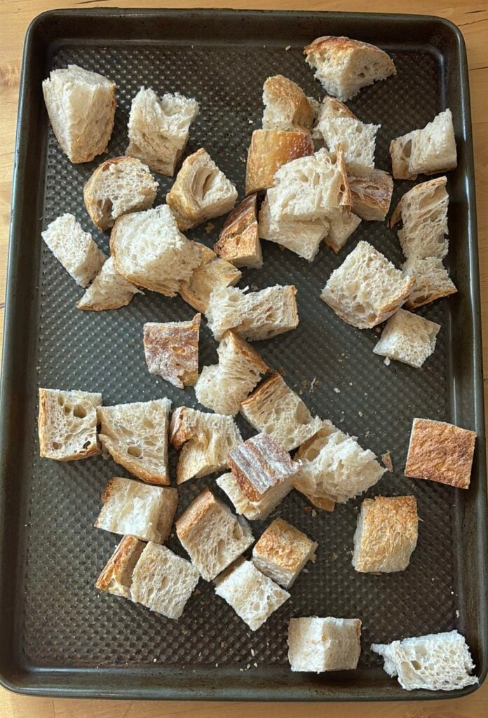 cubes of stale sourdough bread on a baking sheet 
