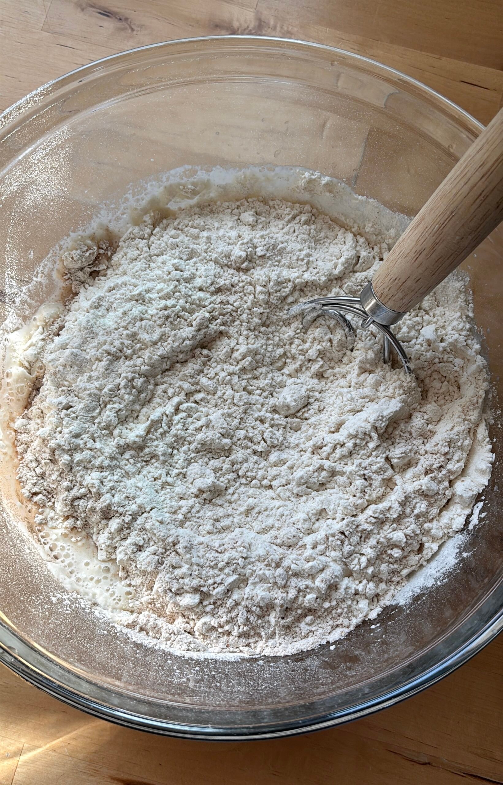 a bowl of flour and a dough whisk