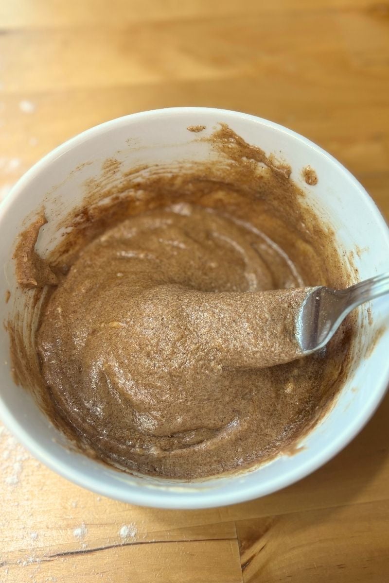 a white bowl of sourdough protein cinnamon roll filling with a fork in it.
