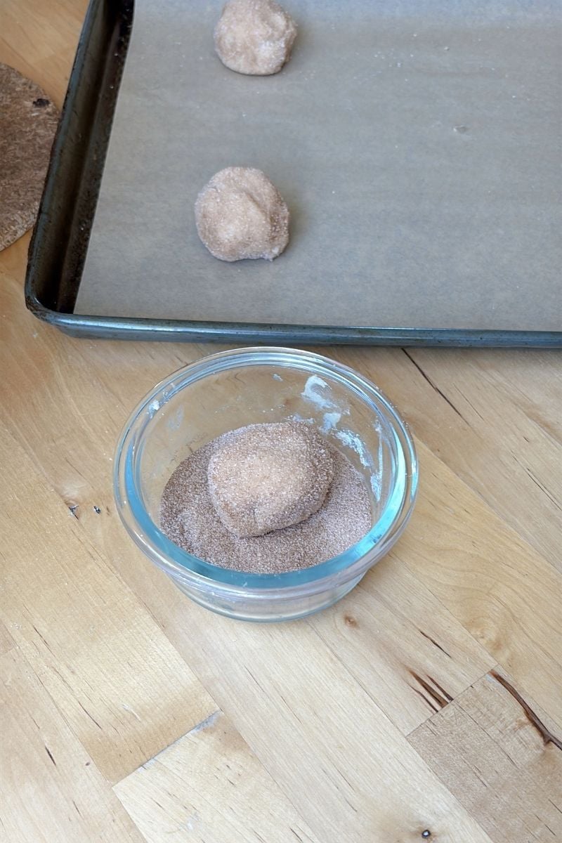 Rolling sourdough snickerdoodle dough in cinnamon sugar.