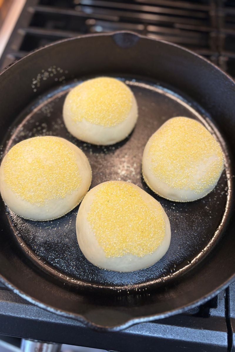 Protein Sourdough English Muffins cooking in a cast iron skillet